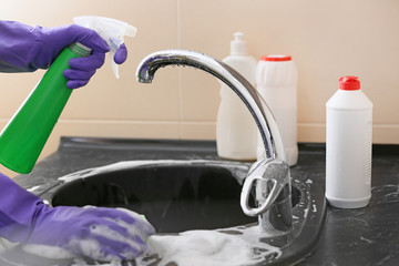 Woman cleaning sink in kitchen