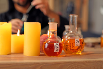 Flasks with potion and candles on table in alchemist's laboratory