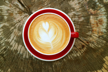 Top View of Hot Cappuccino Coffee in a Red Cup Served on Tree Stump Table