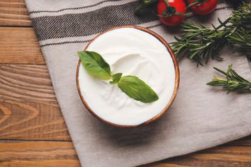 Bowl with tasty sour cream on table