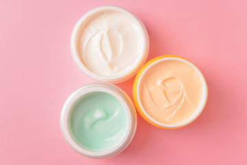Jars of cosmetic cream on color background
