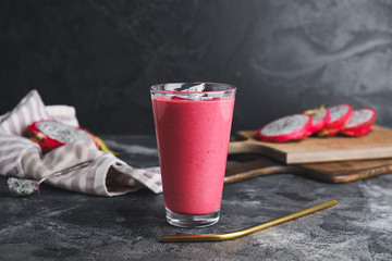 Glass of dragon fruit smoothie on dark background