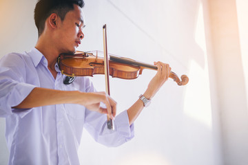 A musician man is practicing the violin playing with the melodiousness. Selected focus.