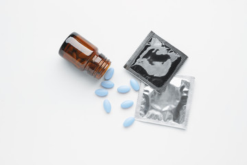 Bottle with sex pills and condoms on white background