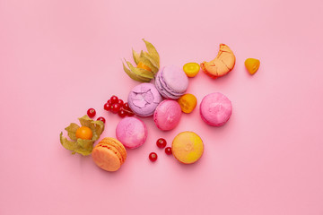 Tasty macarons with fruits on color background
