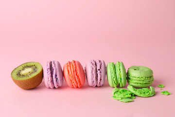 Tasty macarons with kiwi on color background