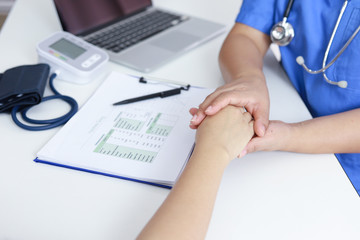 Doctor holding patient's hand, and reassuring woman patient helping hand concept.