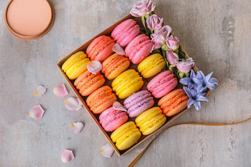 Gift box with tasty macarons on table