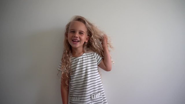 Playful blond girl with wet hairs after bath pose on white wall. Gimbal motion