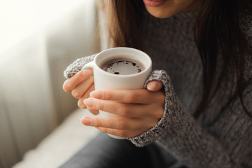 The girl warms her hands on a coffee mug close-up.
