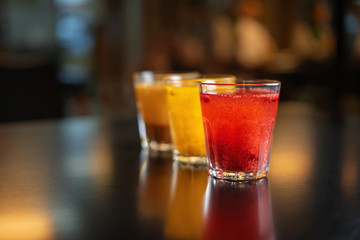 Three drinks of berries and fruit on a black table against the background of the restaurant's interior.