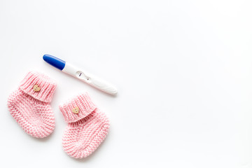 Positive pregnancy test. Baby girl concept with pink booties on white background top-down copy space