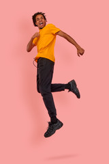 Full length body size view of nice attractive cheerful cheery glad content dark skinned guy jumping in the air running quickly rapidly fast late hurry-up meeting, isolated over pink background