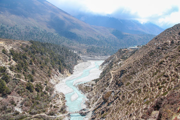 Imja Khola river flows in mountain valley in Himalayas. Panboche village is located on cliff near...