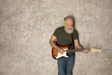 Bearded elderly man is playing guitar