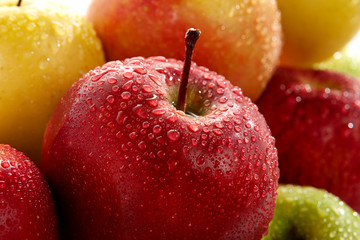 Ripe apples of different varieties in droplets of water close-up.