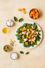 Salad with pumpkin and basil - near ingredients - on beige background top-down