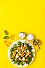 Fototapeta na wymiar Salad with pumpkin and basil - near ingredients - on yellow background top-down copy space
