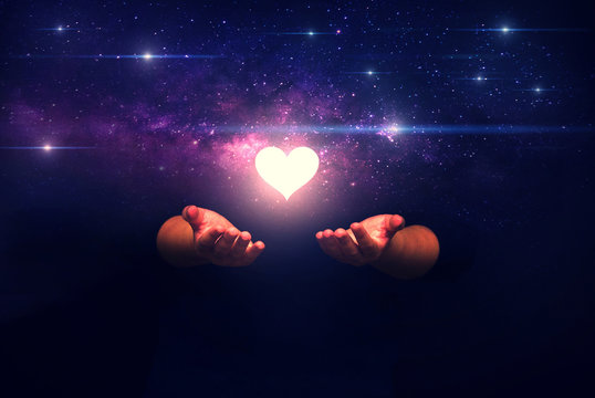 Spiritual image: hands with shining heart shape and spaceship ,Love from universe and love from gods concept.