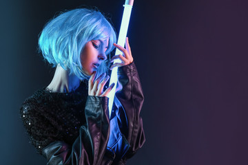 Toned portrait of beautiful woman with neon lamp on dark background