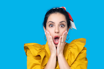 Young woman in a mustard dress looking shocked