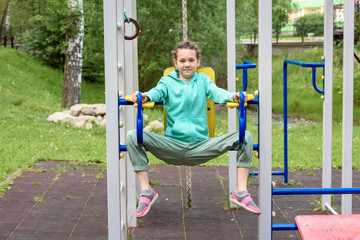 Girl with dreadlocks on her head on iron bars in the playground.