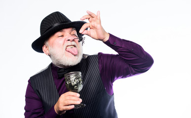 i am the treat. happy halloween. mature man magician in witch hat. barman make cocktail for halloween party. evil wizard cooking magic potion with spider. halloween holiday costume