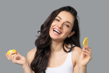 Beautiful dark-haired girl holding oranges in her hands and laughing