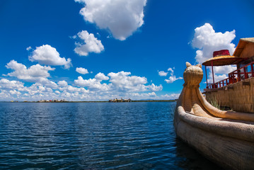 Uros floating island and Totora traditional boat on Titicaca lake near Puno city, Peru