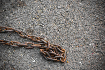 Rusty heavy chain on asphalt is close