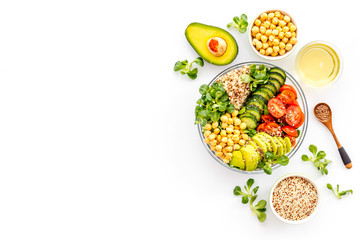 Vegan Buddha bowl. Avocado, quinoa, tomato, spinach and chickpeas vegetables salad on white table...