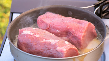 Close up Raw seasoned angus steak fried on hot pan with smoke and steam rise from steak.