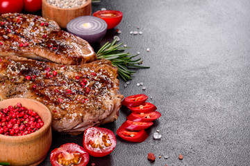 Fresh delicious juicy steak on the bones with vegetables and spices against a dark background