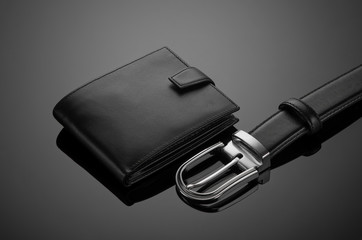 Fashionable leather men's wallet and belt on a black background - obrazy, fototapety, plakaty