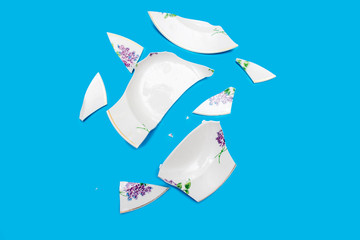 Shards of a broken plate on a blue background. Small pieces of chopped dishes