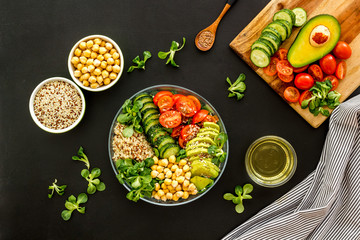 Veggie bowl. Vegetable salad with quinoa, avocado, tomato, spinach and chickpeas - on black table. Top view