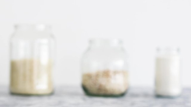 non-perishable pantry ingredients, glass jars with oats flour and rice and camera defocusing from eye-level perspective
