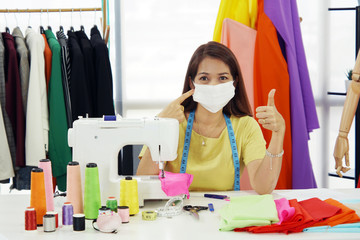 senior woman designer wear mask while she is working in workplace to protect corona virus