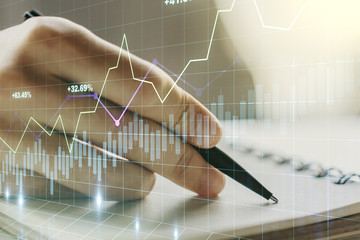 Double exposure of abstract creative financial diagram with hand writing in notebook on background,...