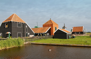 Fototapeta na wymiar View of traditional Dutch farm houses along a canal in spring at the Zaanse Schans, Zaandam, Netherlands