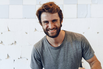 Pleased joyful bearded man against rough wall, portrait