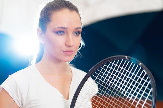 Close up portrait of a young attractive woman tennis player holding tennis racket