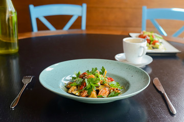 Salad with fresh grilled vegetables on a blue plate on black rustic wooden background.