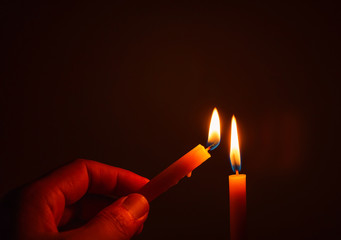People's hands are lit by candles in the dark. Design for the background, hand with candle, lighting candles, Burning candle on black background, Candle in hand, Candle in the dark.
