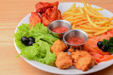 Close up gourmet main dish for dinner with crispy fried chicken, french fries and veggies on white plate.