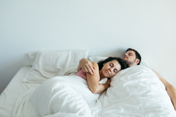 couple sleeping in bed with white sheets