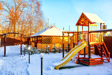 Slide with yellow wooden gazebo on the Playground for children in the yard on a Sunny winter day