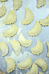 Uncooked russian vareniki on metal tray with flour. Process of making vareniki.