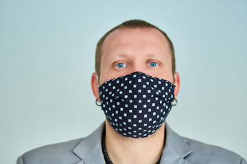 Portrait of man wearing black mask at grey background.