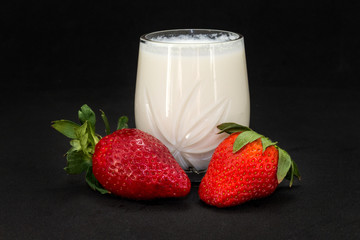 Fresh strawberries with milk on a black background